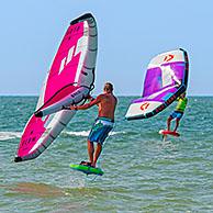 Wing foiling / wing surfing on the North Sea showing wingboarders / wing boarders standing on foilboard / hydrofoil board and holding inflatable wing